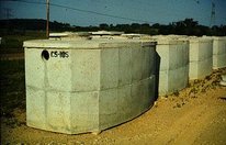 Four rectangular concrete basins lined up in a row with power lines in the background.